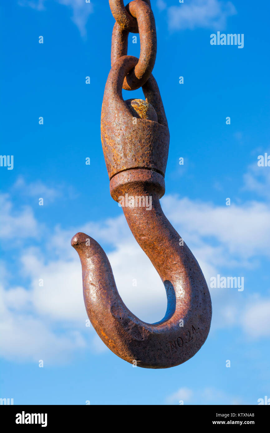 Un grande penzolanti arrugginendo metallo paranco gancio girevole contro un naturale blu cielo nuvoloso sfondo. Trovato presso il vecchio Burra stazione ferroviaria, Sud Australia Foto Stock