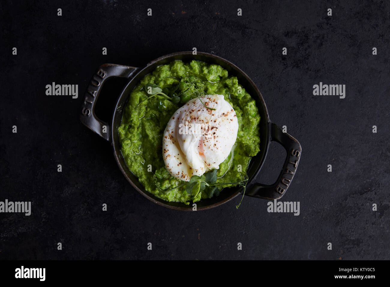 Purè di avocado con uovo in camicia, pepe e coriandolo Foto Stock