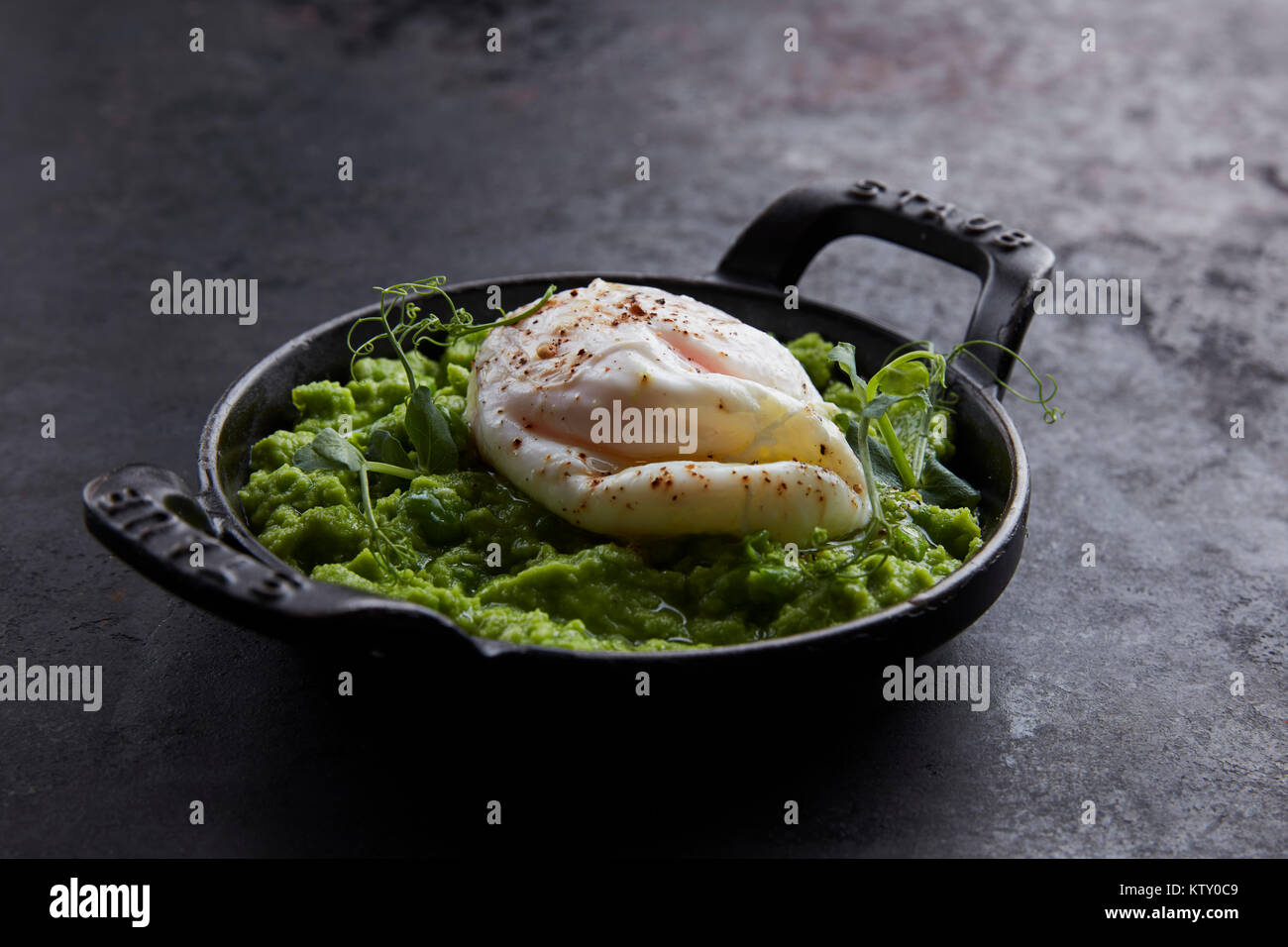 Purè di avocado con uovo in camicia, pepe e coriandolo Foto Stock