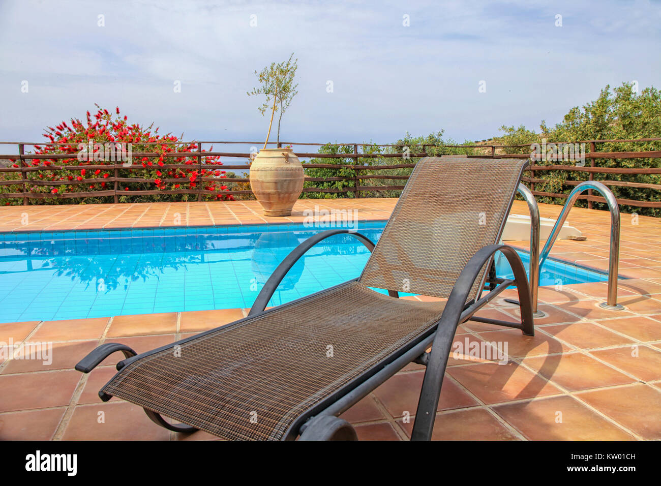 Svuotare sdraio vicino a un cristallo azzurro piscina Foto Stock