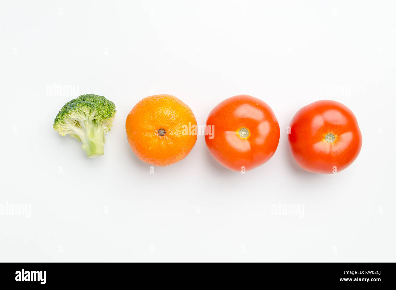 Fila di verdure fresche: pezzo di broccoli, Mandarine clementine/e due pomodori, isolato su sfondo bianco. Foto Stock