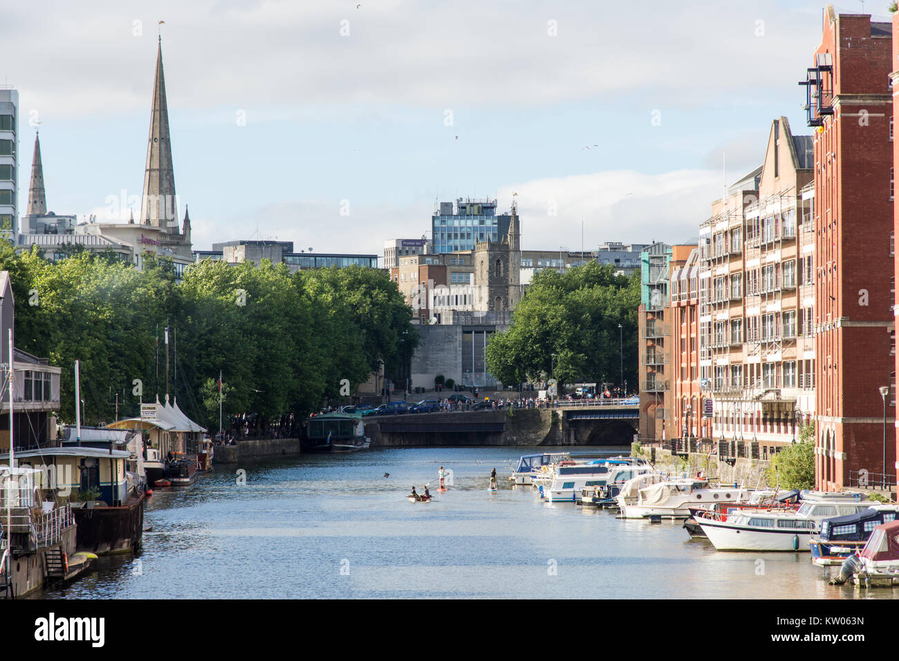 Bristol, Inghilterra - Luglio 17, 2016: la gente di riga e paddleboard a fianco di barche e magazzino convertito edifici di Redcliffe Wharf sul Bristol's Floatin Foto Stock