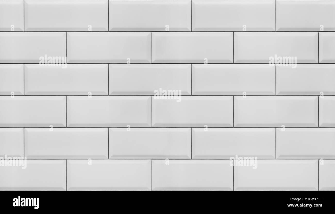 Immagine di una parete rivestita con piastrelle bianche con bordi smussati, per utilizzare come sfondo senza giunture. Foto Stock