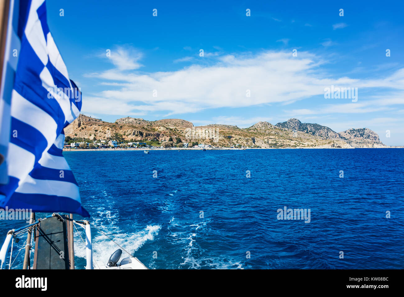 Vista della bandiera greca sulla barca e Stegna beach behaind (RHODES, Grecia) Foto Stock