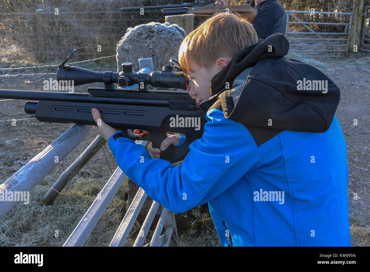 Ragazzo adolescente sparando un fucile ad aria compressa in campagna su un freddo gelido giorno Foto Stock