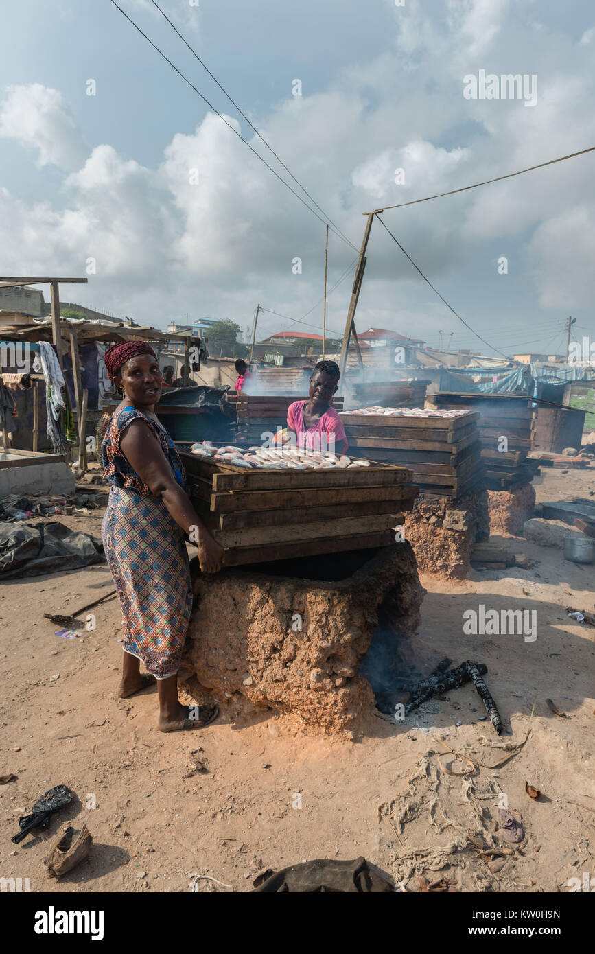 Due donne di fumare pesce su un forno di argilla, Jamestown Villaggio di Pescatori, Jamestown, Accra, Ghana, Africa Foto Stock