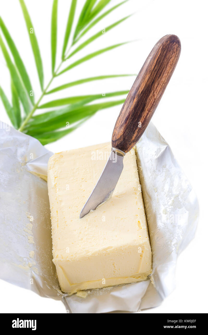 Salate burro cremoso nel suo imballo di carta con coltello piantato nel burro su sfondo bianco Foto Stock