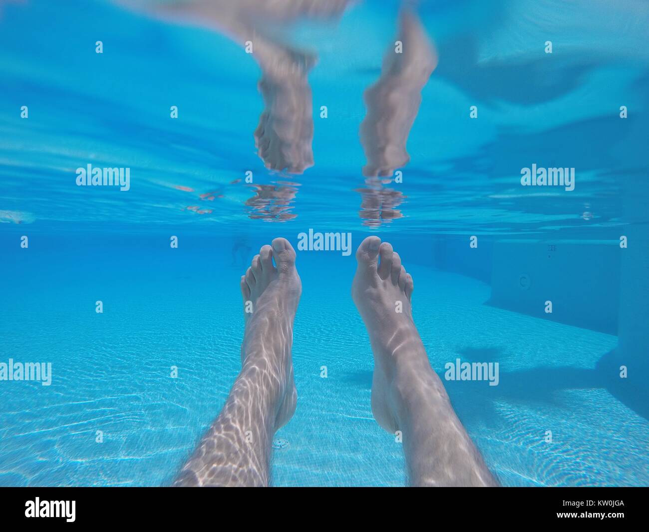 Riprese subacquee di piedini maschio in blu chiaro piscina con acqua in presenza di luce solare Foto Stock