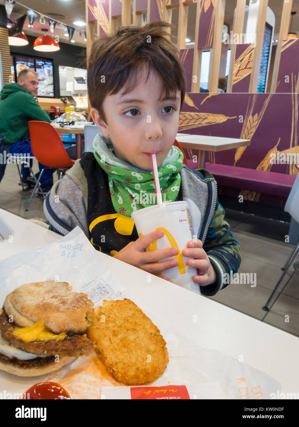 Un giovane ragazzo godendo un McDoanld della prima colazione in un McDonald's ristorante fast food. Foto Stock