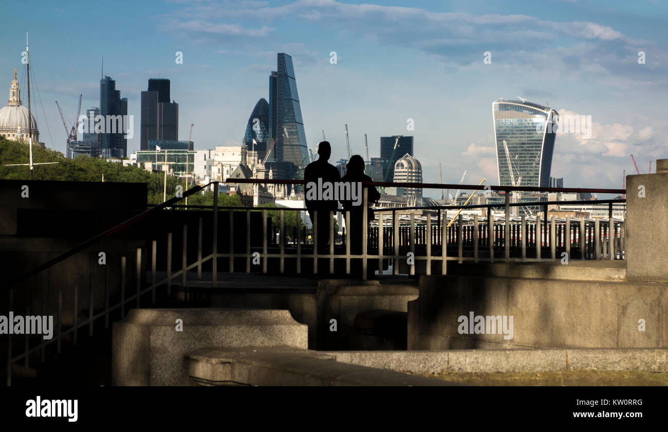 Paio di guardare verso la città di Londra da una piattaforma di osservazione sulla sponda nord del fiume Tamigi sotto il ponte di Waterloo, London, Regno Unito Foto Stock