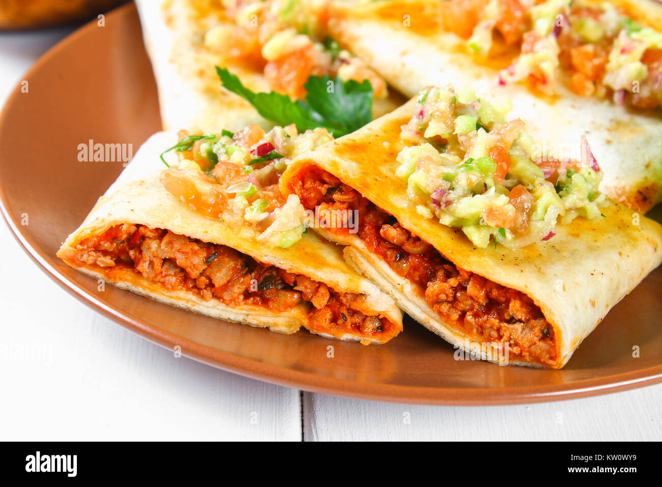 Tradizionale piatto messicano - chimichanga. Torta di mais con carne macinata, pepe, cipolla, aglio, origano, zira e salsa guacomole da avocado Foto Stock