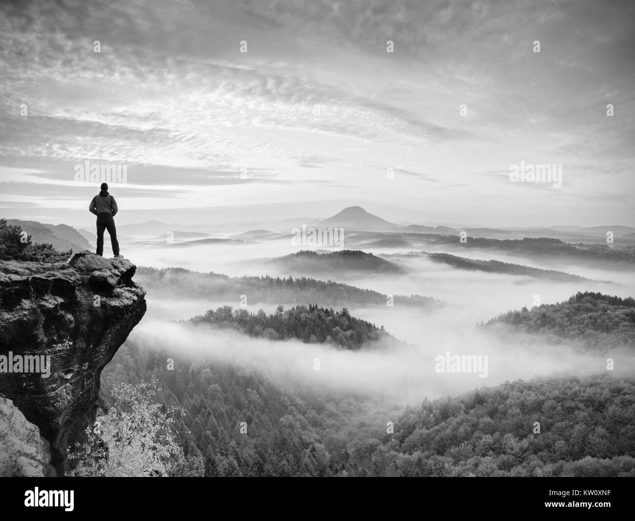 Escursionista è in piedi sul picco di arenaria nel parco roccioso e guardare oltre il misty e nebbiosa mattina valle a Sun. bel momento miracolo della natura. Escursionista s Foto Stock