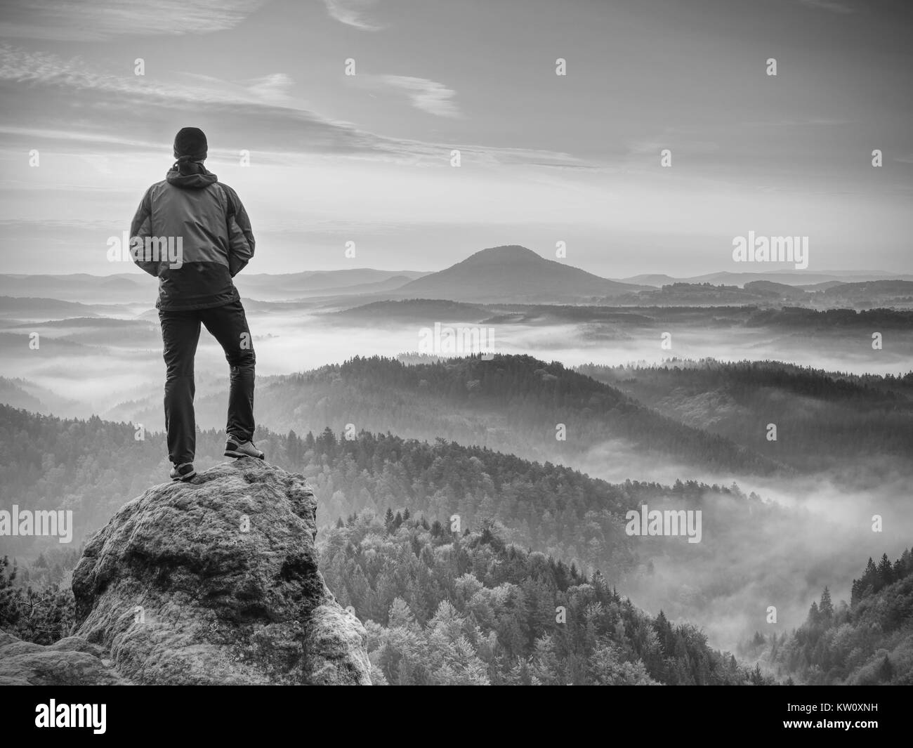 Escursionista è in piedi sul picco di arenaria nel parco roccioso e guardare oltre il misty e nebbiosa mattina valle a Sun. bel momento miracolo della natura. Escursionista s Foto Stock