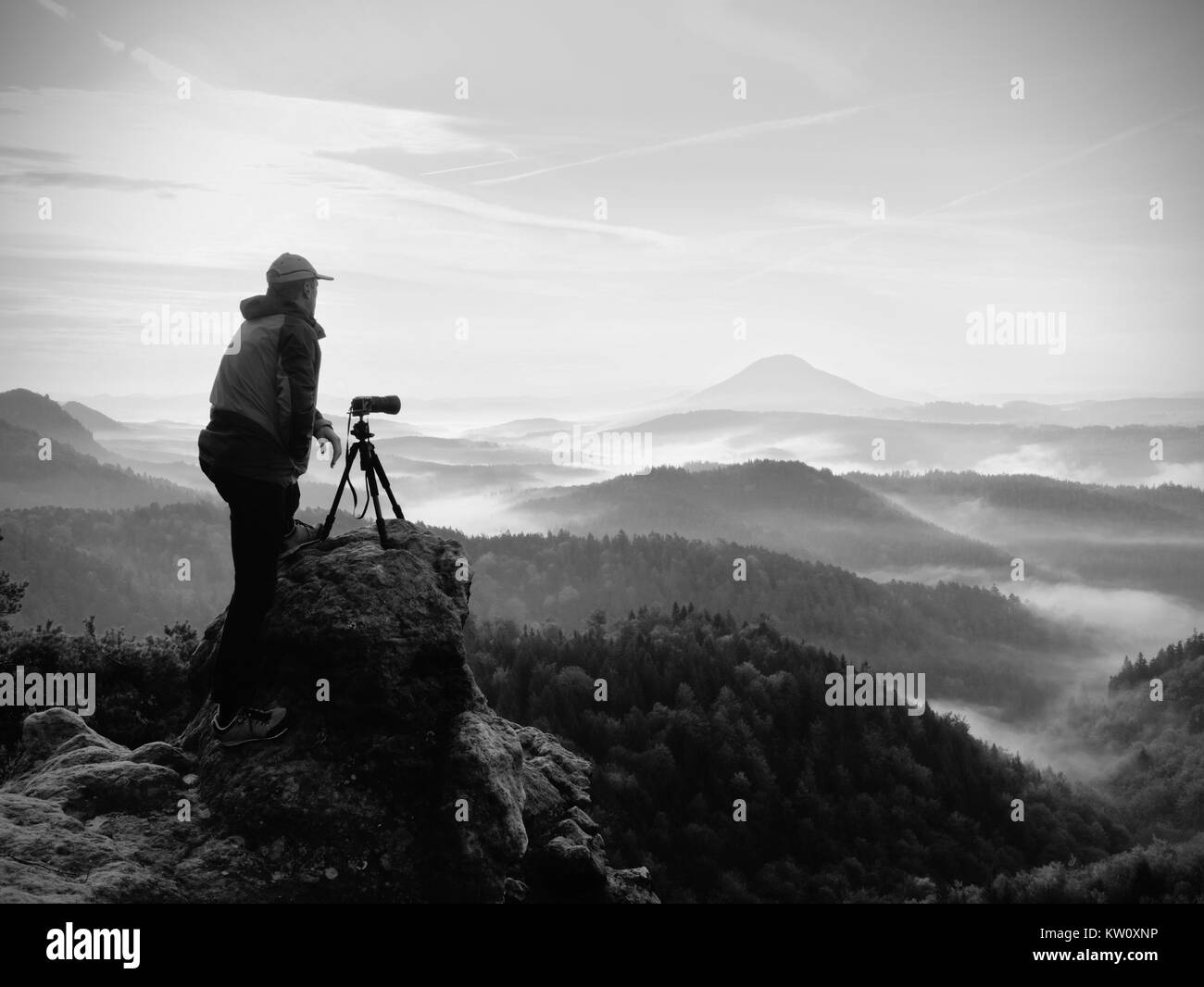 Fotografo guarda nel paesaggio e ascoltare il silenzio. L'uomo Preparazione della fotocamera alla porta foto impressionante di caduta Misty Mountains. Foto Stock