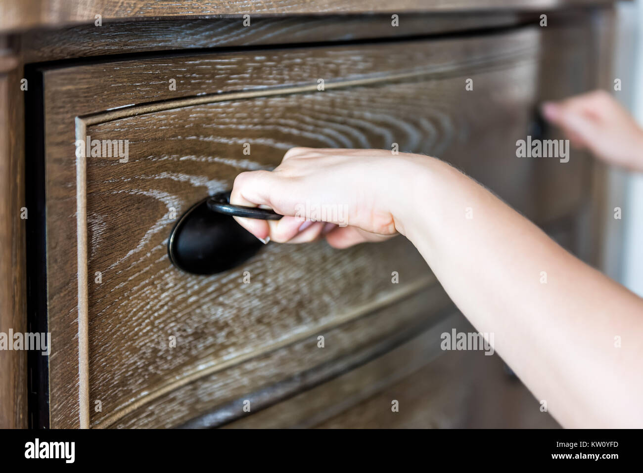 Primo piano della cassa di legno cassetto in camera da letto con luce naturale in casa di staging, casa appartamento il modello e la donna con le mani in mano la sua apertura Foto Stock