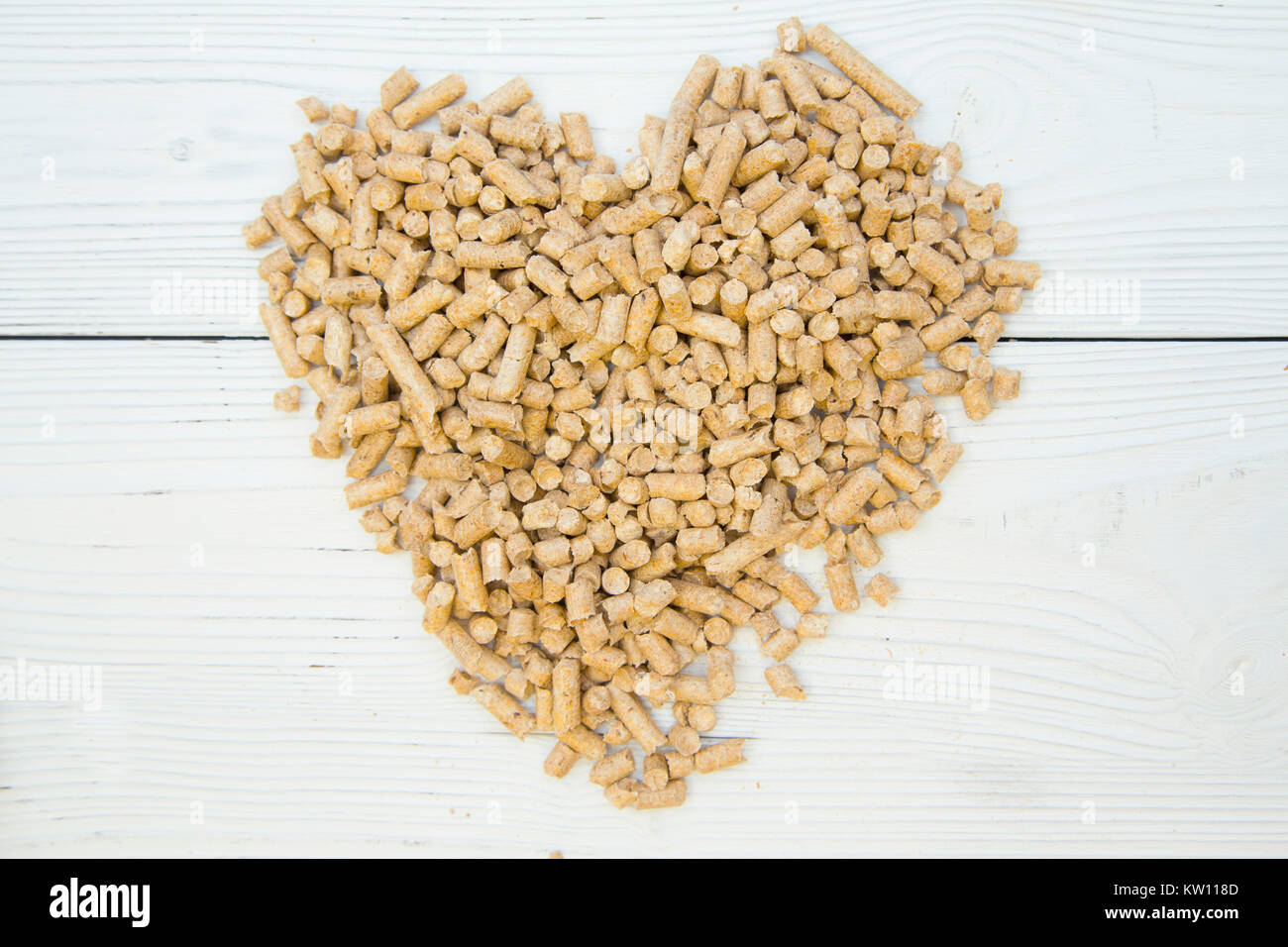 Pet care concetto. Un cuore fatto di pet wc di riempimento. Tappapori per animali domestici- gatti, topi, ratti, conigli, criceti. Bianco sullo sfondo di legno. Foto Stock