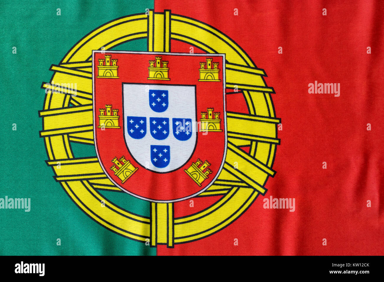 Una bandiera portoghese è raffigurato come esso giace su una superficie piana. Lo stemma in tra il grassetto colori rosso e verde è un grande simbolo per il countr Foto Stock