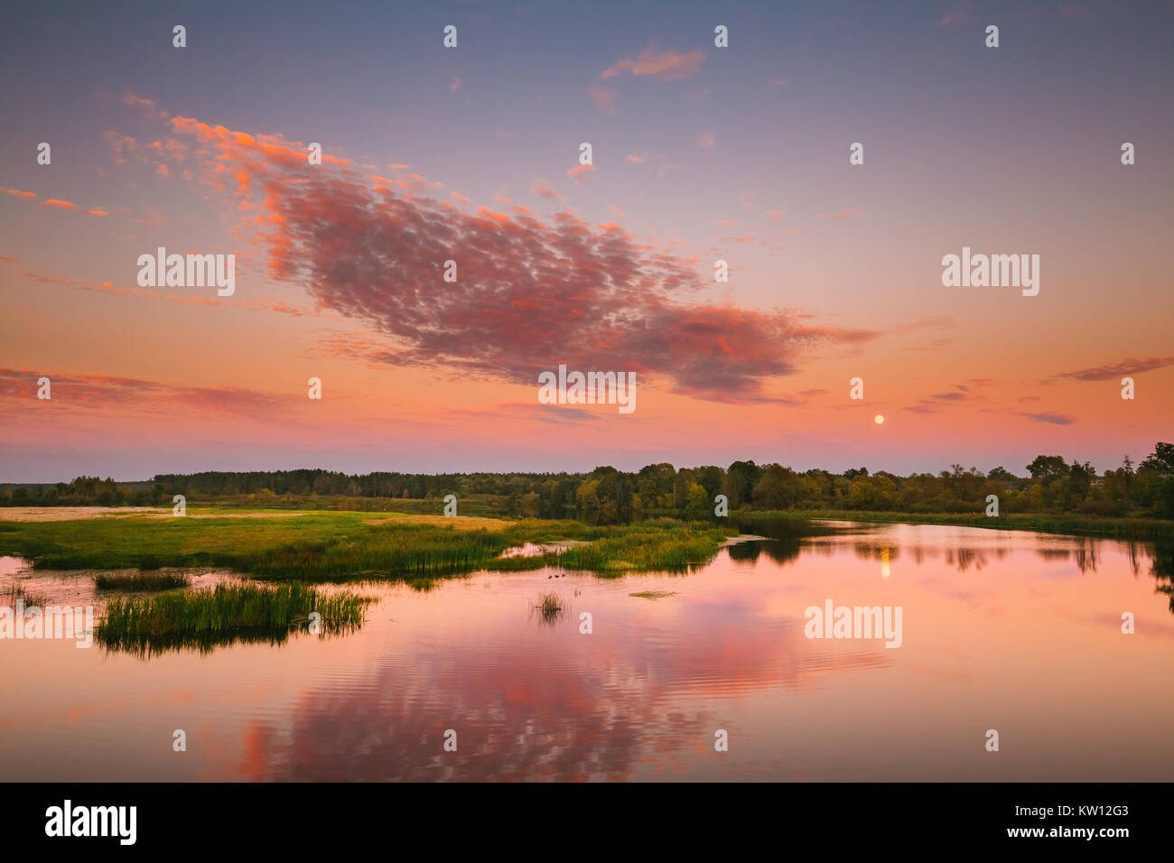 Paesaggio fluviale in Bielorussia o la parte europea della Russia nel tempo al tramonto di sera d'estate. Luna crescente per l'acqua del lago o fiume. La natura a Sunny sera. Foto Stock