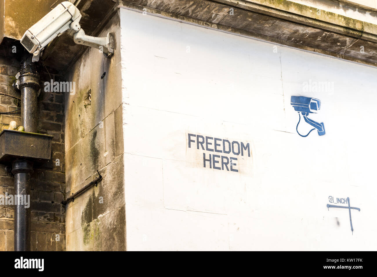 Stencil art graffiti 'libertà' concetto su una parete bianca con una videocamera di sorveglianza accanto ad esso nel centro città di Southampton, England, Regno Unito Foto Stock