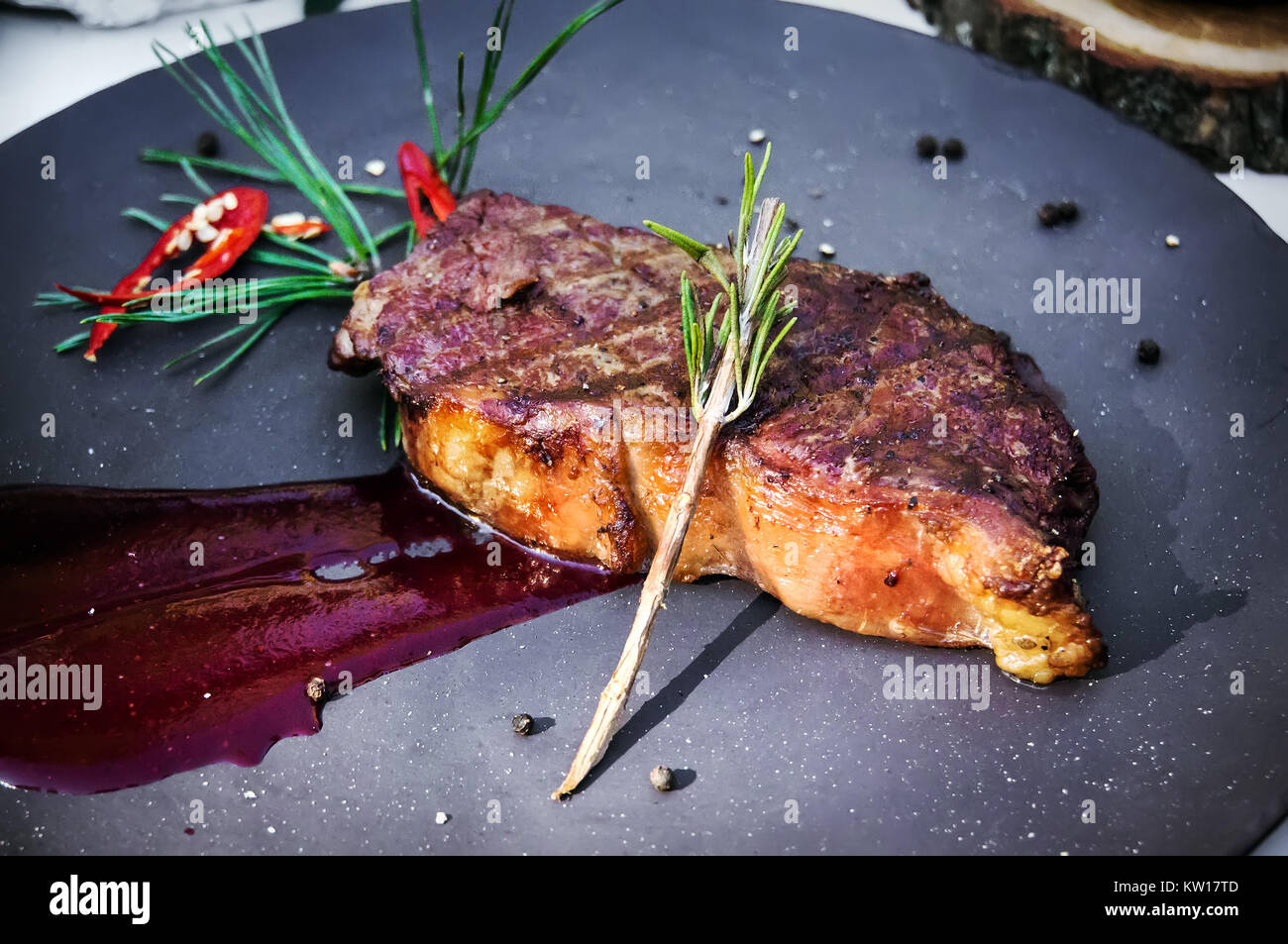 Filetto alla griglia di carni bovine condito con pomodoro salsa rossa abete rosso ramoscello sulla piastra. Bistecca cotta in Siberia Foto Stock