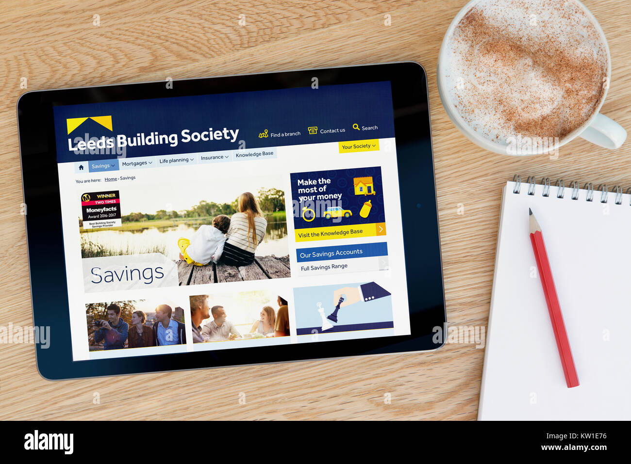 La Leeds Building Society sito web su un iPad dispositivo tablet, appoggiato su un tavolo di legno accanto a un blocco note, matita e tazza di caffè (editoriale solo) Foto Stock