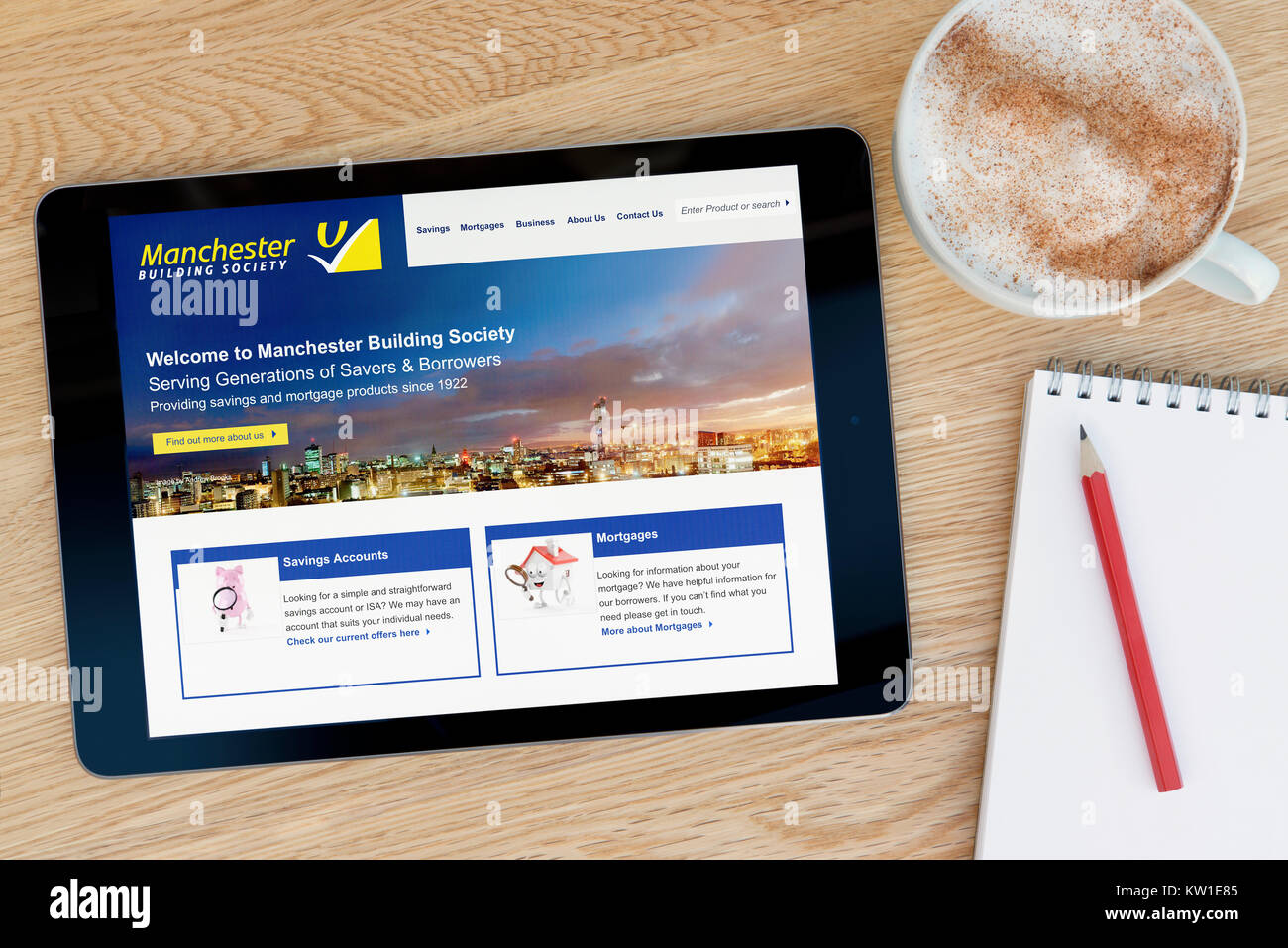 La Manchester Building Society sito web su un iPad dispositivo tablet, appoggiato su un tavolo di legno accanto a un blocco note, matita e tazza di caffè (solo editoriale Foto Stock