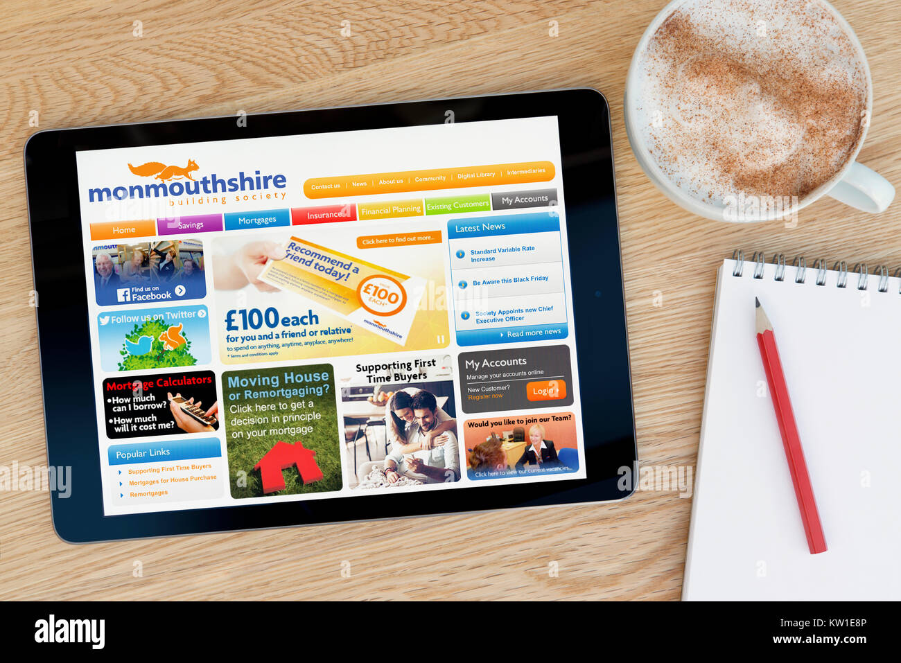 Il Monmouthshire Building Society sito web su un tablet iPad, appoggiato su un tavolo di legno accanto a un blocco note, matita e tazza di caffè (editoriale solo) Foto Stock