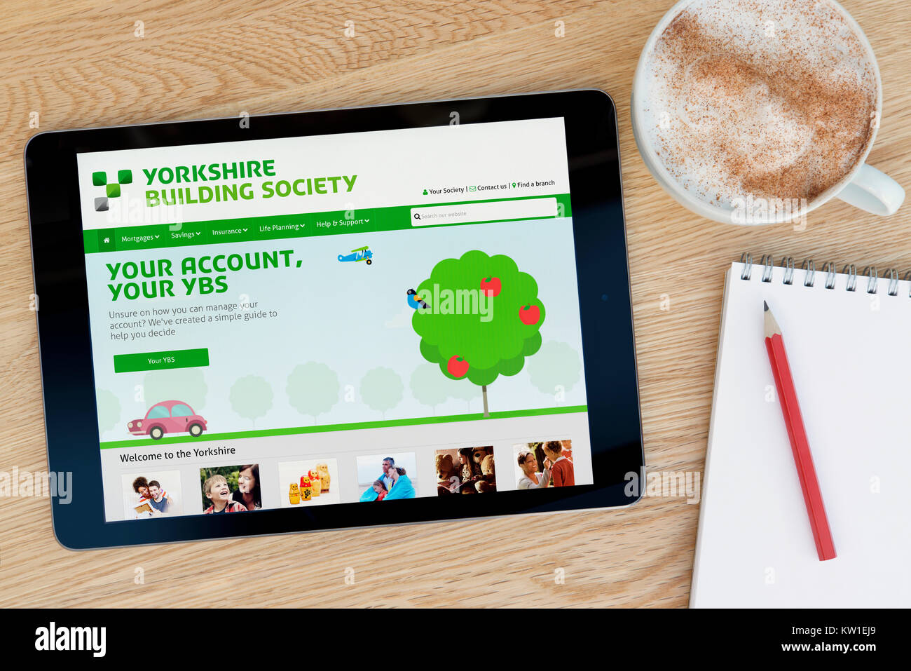 La Yorkshire Building Society sito web su un iPad dispositivo tablet, appoggiato su un tavolo di legno accanto a un blocco note, matita e tazza di caffè (editoriale solo) Foto Stock