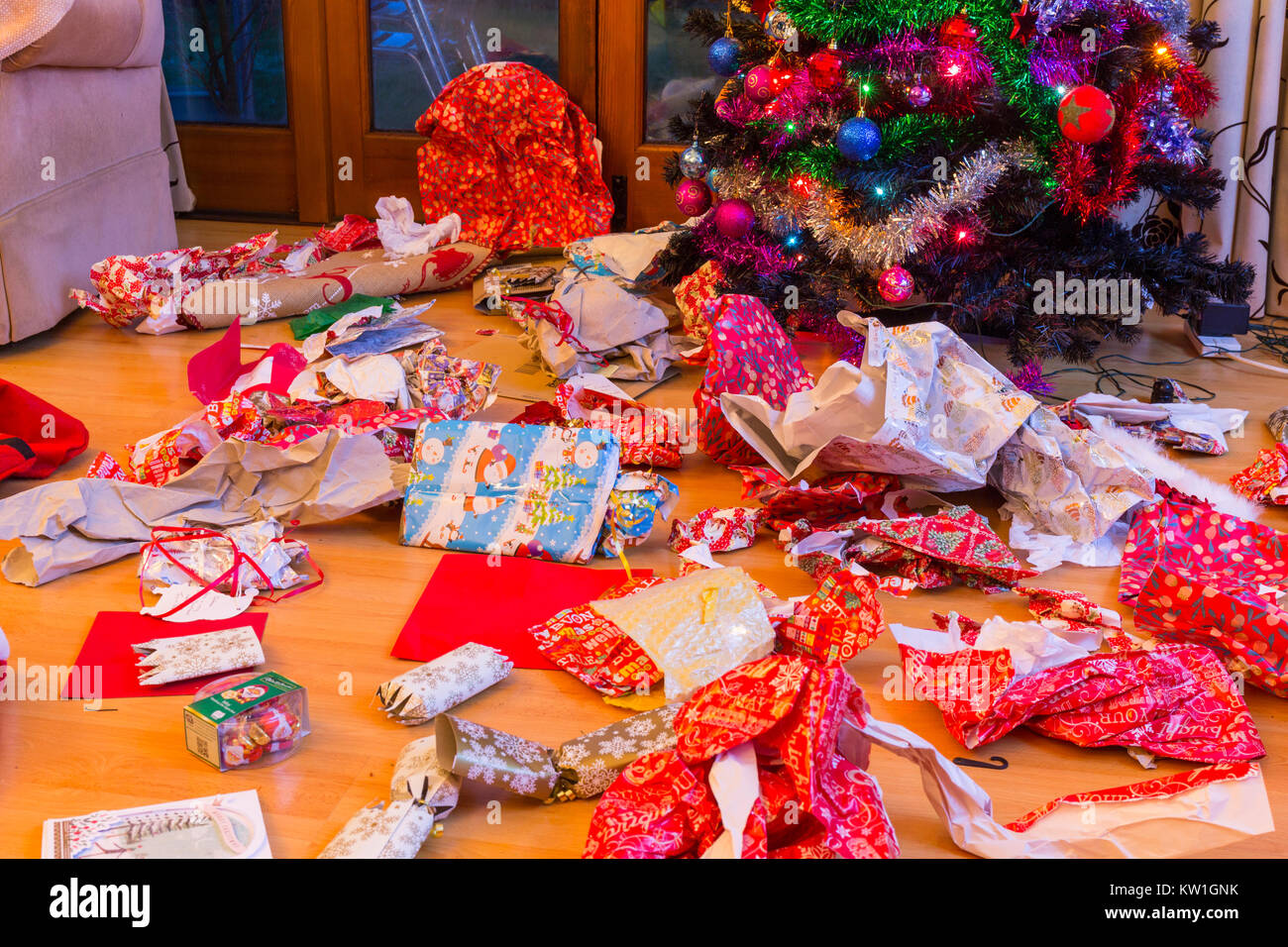 Postumi di Natale. Usato carta di imballaggio di Natale lasciata sul pavimento sotto l'albero di Natale. Foto Stock