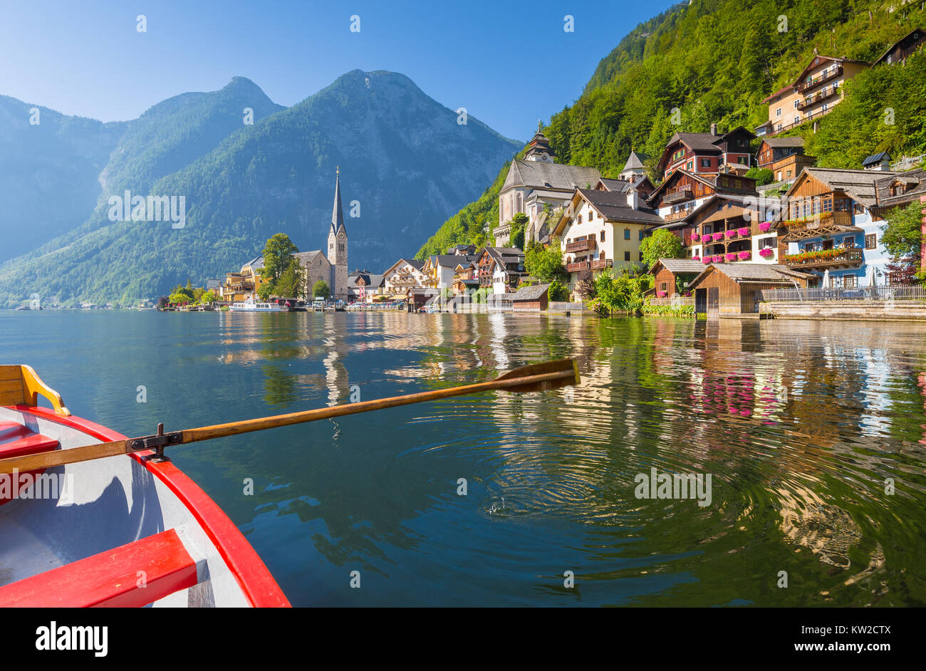 Scenic vista da cartolina famosa Hallstatt borgo lacuale nelle Alpi austriache con legno tradizionale barca a remi in bella luce del mattino su una sun Foto Stock