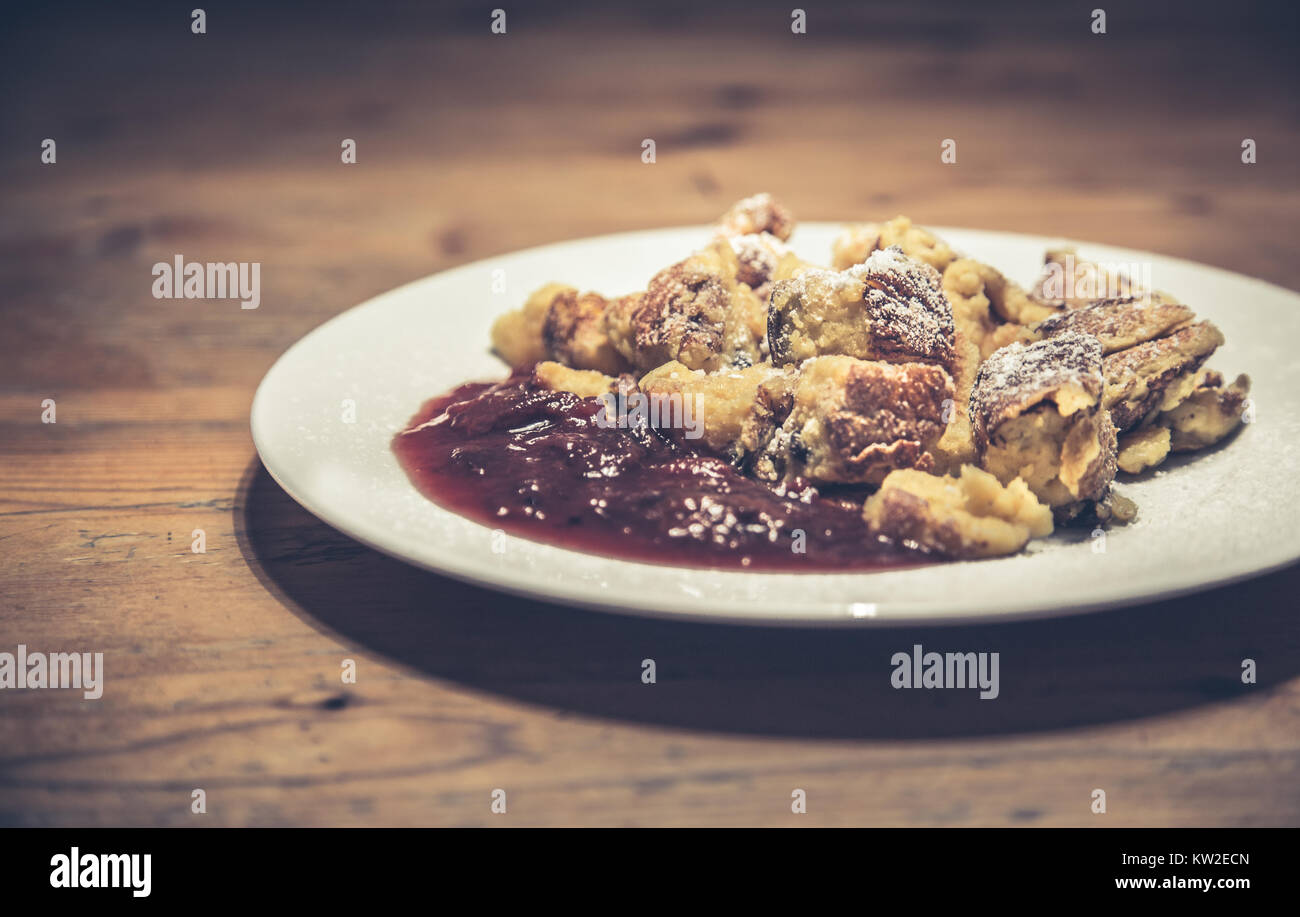 Tradizionale austriaca Kaiserschmarrn pancake dessert servito con composta di prugne su tavola in legno rustico nel retro vintage stile Instagram effetto filtro Foto Stock