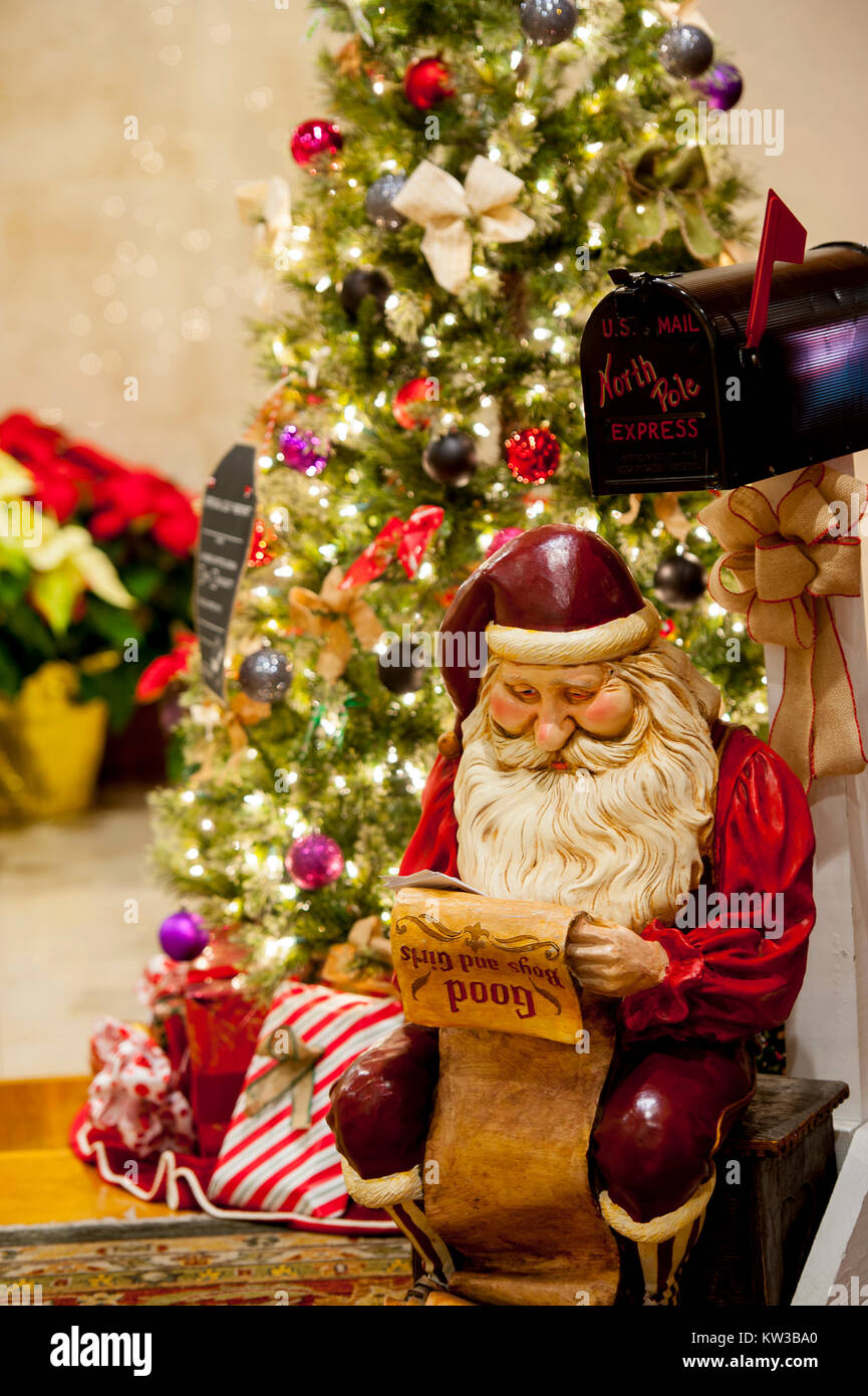 Vacanze a Natale un Babbo Natale in figura è la lettura di un elenco di ragazzi e ragazze naughty o Nizza da un decorate albero Foto Stock