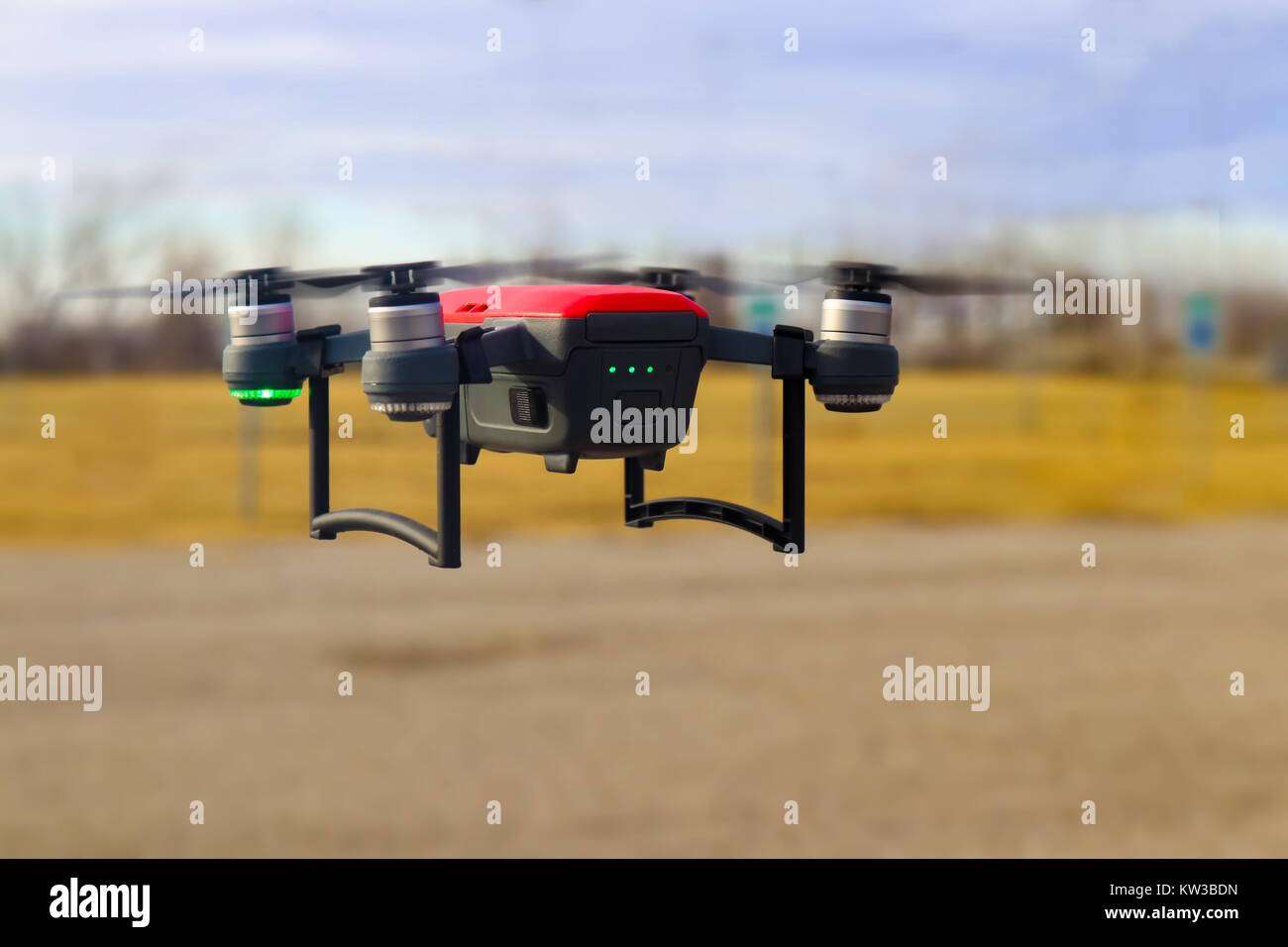 Piccolo rosso e grigio drone in volo con tre quarti della carica della batteria contro sfondo sfocato - inverno Foto Stock