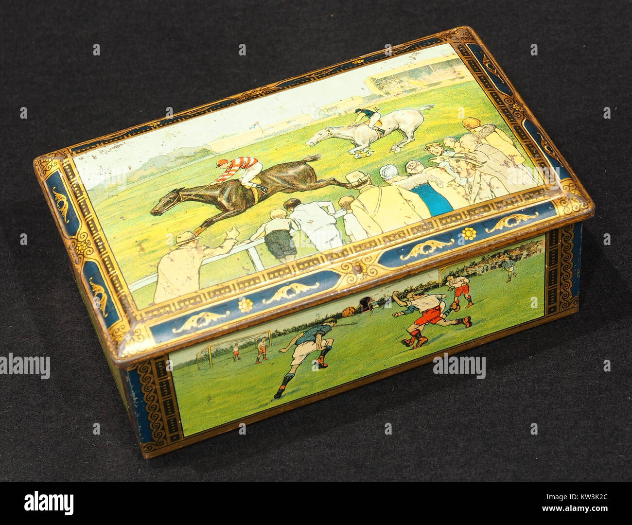 Questa scatola di biscotti dei primi anni '1930 presenta immagini vintage di scene sportive, che rappresentano uno sguardo nostalgico sulla cultura sportiva del tempo. Questi oggetti da collezione evidenziano l'intersezione tra cultura popolare e oggetti di uso quotidiano. Foto Stock