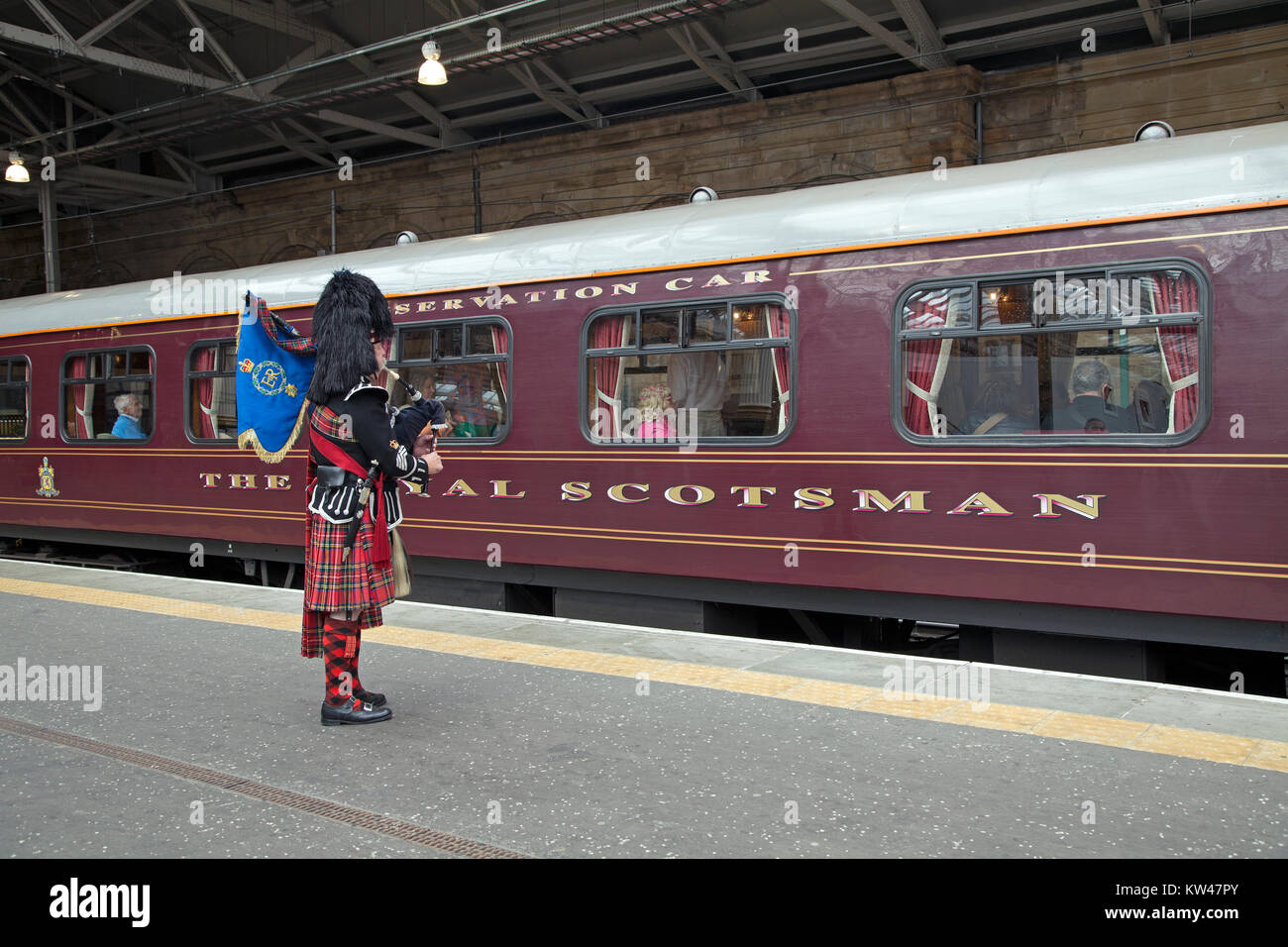 Un piper saluto il Royal Scotsman in treno la stazione ferroviaria Waverley di Edimburgo, Scozia. Foto Stock