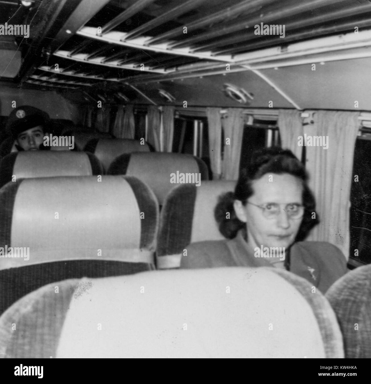 Donna matura seduto da solo su un bus, con uno sguardo di preoccupazione, un giovane soldato in uniforme è visibili diversi posti a sedere dietro di lei, la città di New York, New York, 1952. Foto Stock