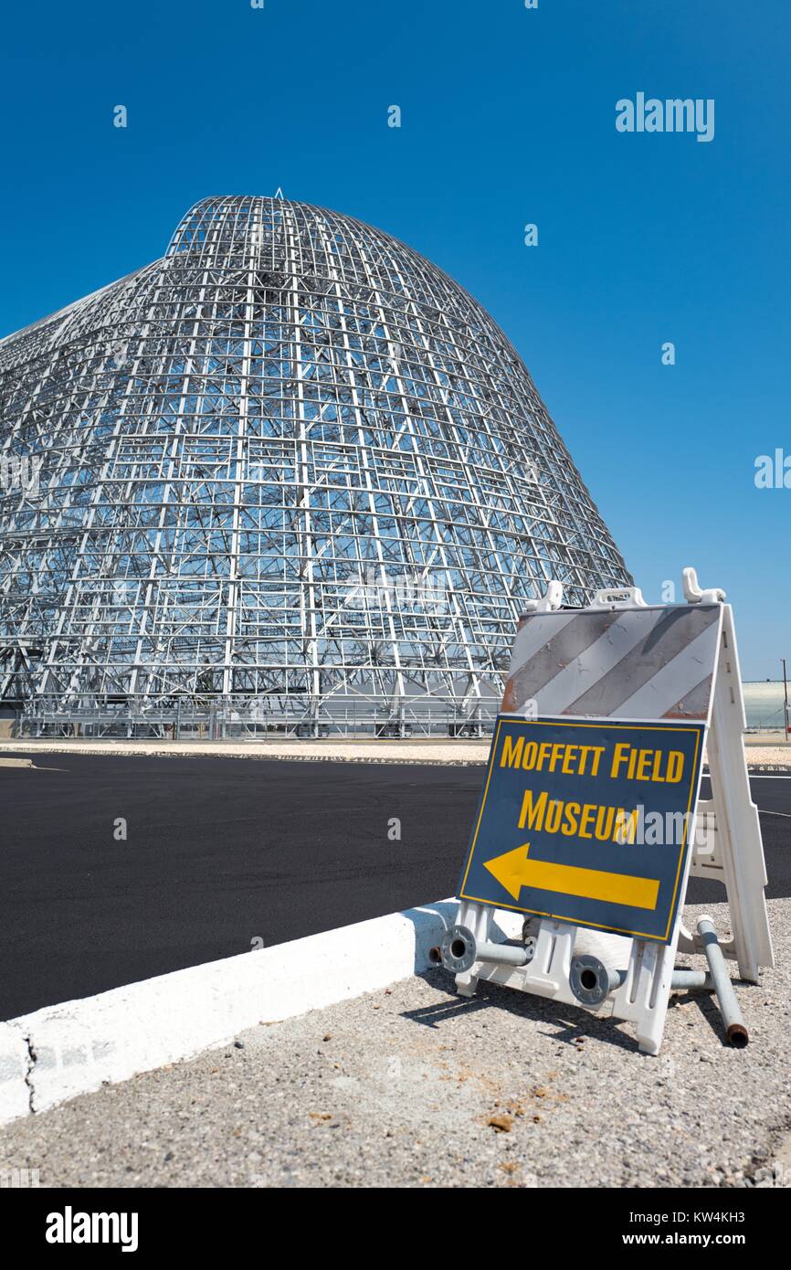 Firmare con la freccia dirigere i visitatori del campo di Moffett museo storico, con Hangar una visibile in background, all'interno dell'area protetta della NASA Ames Research Center campus in Silicon Valley Town di Palo Alto, California, 25 agosto 2016. Hangar uno, che è tra le più grandi del mondo free-standing strutture, stata affittata a Google Inc planetario di affiliazione Ventures nel 2016 (insieme a Moffett Field) per 60 anni a un costo di 1,6 miliardi di dollari, contingenti alla ristrutturazione della società la struttura, California. Foto Stock