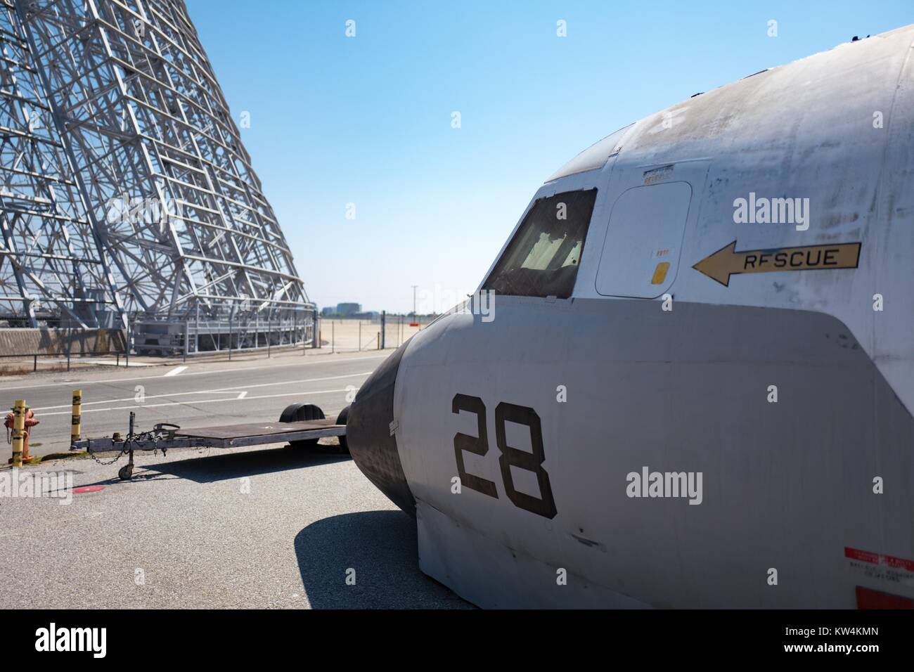 Struttura metallica di hangar si è visibile lungo con la porzione di naso di un aereo militare in mostra al campo di Moffett museo storico, all'interno dell'area protetta della NASA Ames Research Center campus in Silicon Valley Town di Palo Alto, California, 25 agosto 2016. Hangar uno, che è tra le più grandi del mondo free-standing strutture, stata affittata a Google Inc planetario di affiliazione Ventures nel 2016 (insieme a Moffett Field) per 60 anni a un costo di 1,6 miliardi di dollari, contingenti alla ristrutturazione della società la struttura, California. Foto Stock