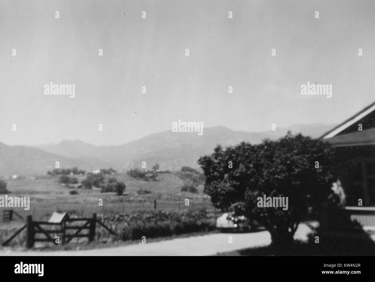 Rurale scena di una fattoria con un piccolo albero accanto a una casa colonica con un cancello, campi e montagne sullo sfondo, Stati Uniti, 1943. Foto Stock