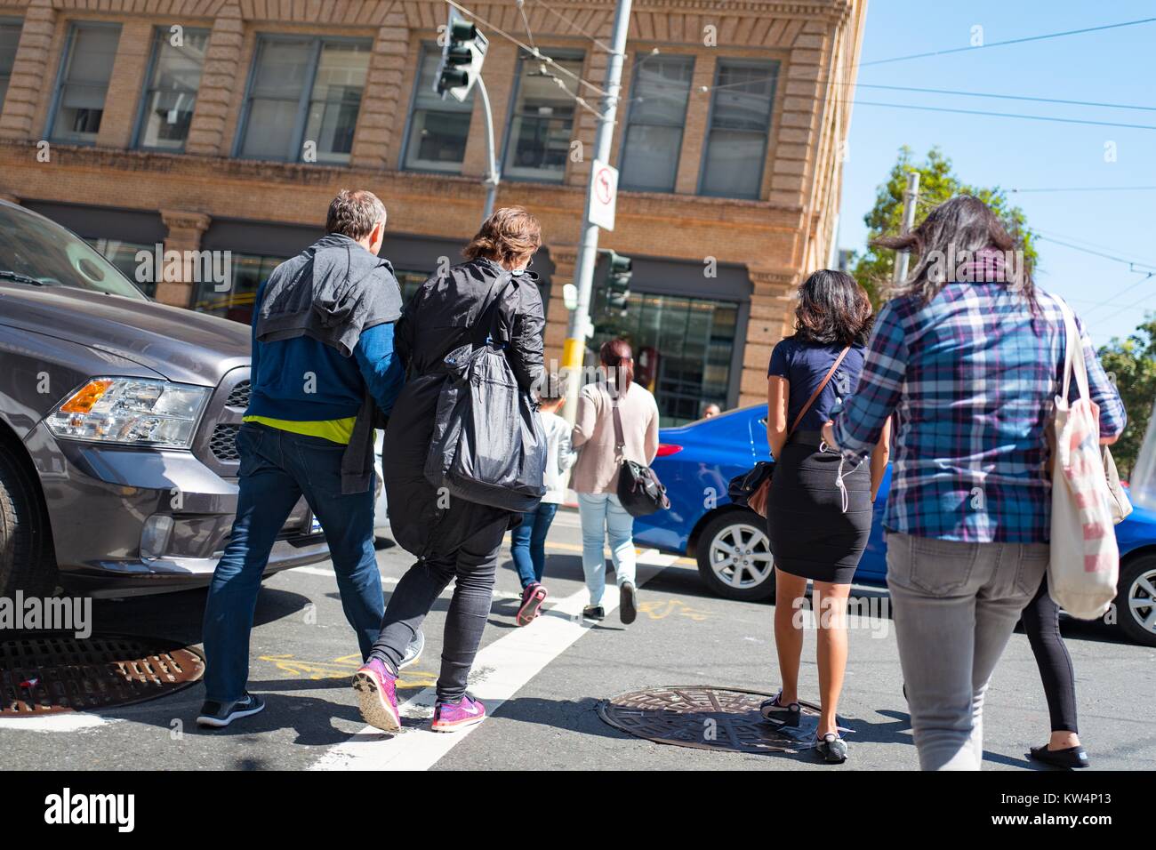 Un gruppo di persone a piedi tra le vetture per attraversare un incrocio di San Francisco, California, 4 settembre 2016. Foto Stock