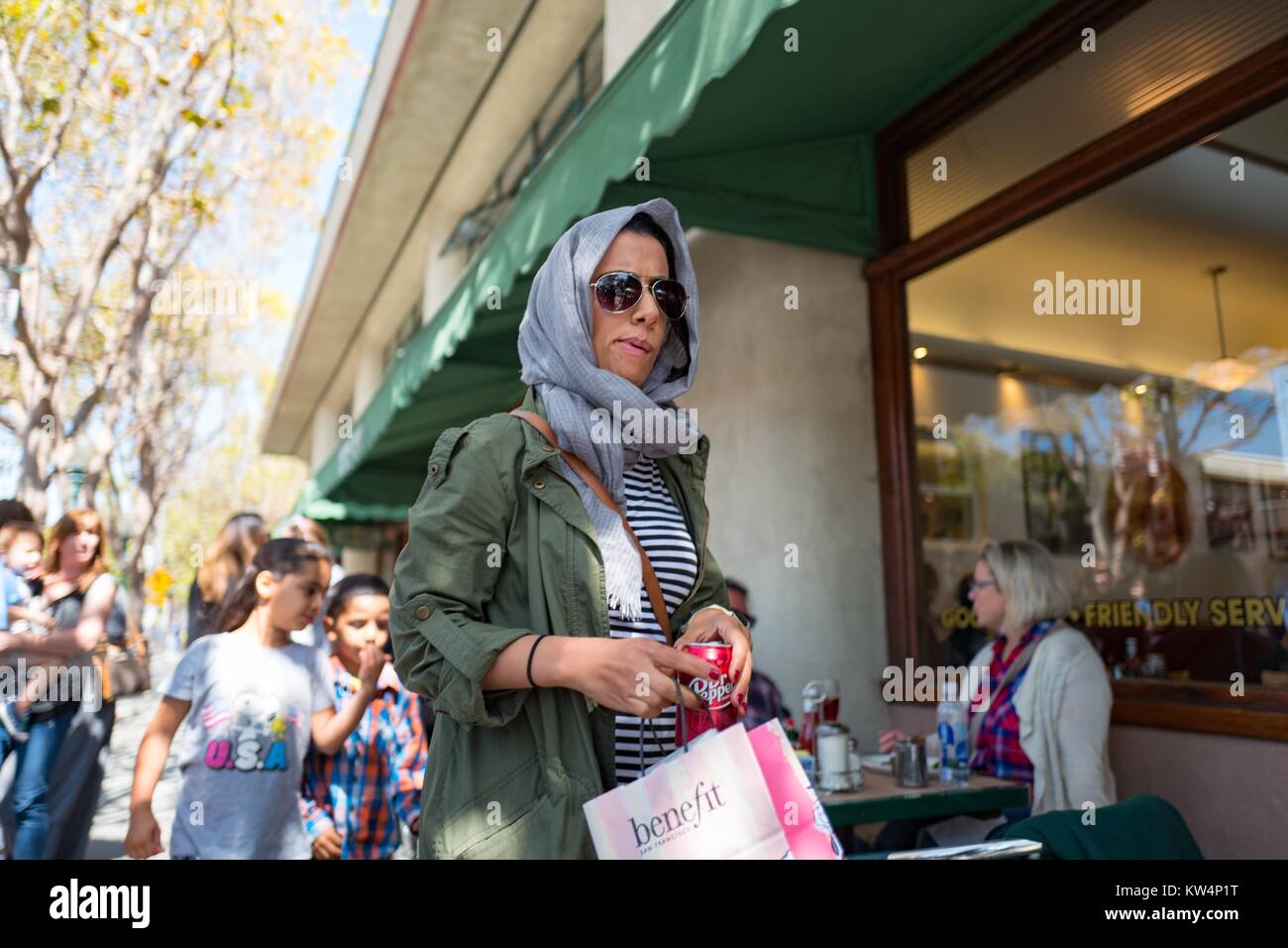 Una donna che indossa gli occhiali da sole e un foulard attorno alla sua  testa passeggiate lungo il marciapiede in quarta strada dello shopping,  Berkeley, California, 4 settembre 2016 Foto stock - Alamy