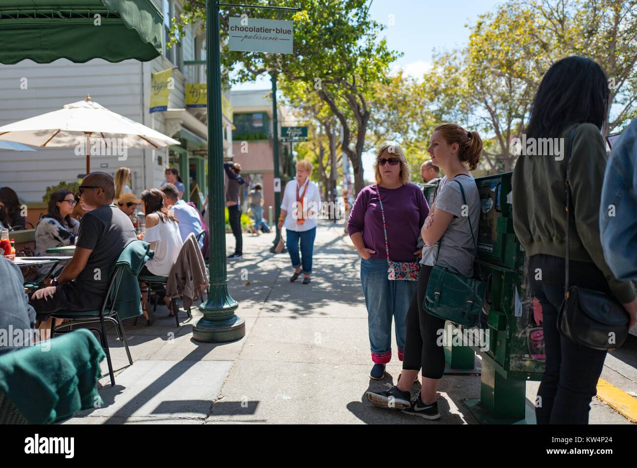 Persone sedersi e mangiare a tavoli esterni a Chocolatier blu mentre altre attendere per tavoli sul marciapiede in quarta strada dello shopping, Berkeley, California, 4 settembre 2016. Foto Stock