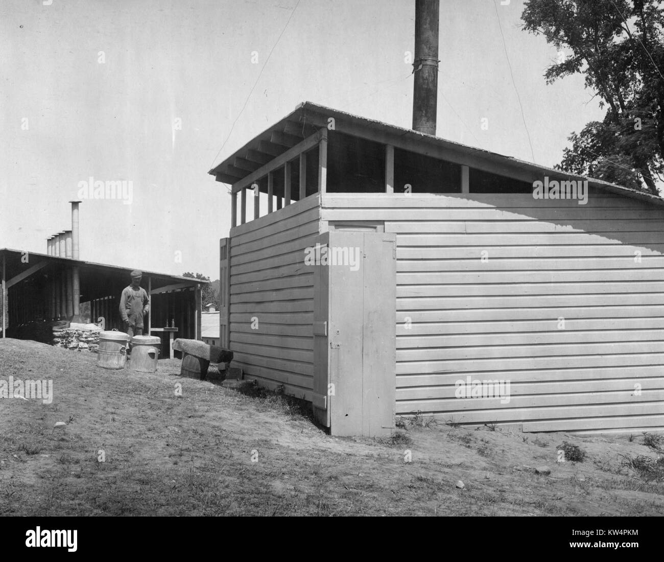 Un lavoratore si erge tra due annessi su un accampamento durante la costruzione di un acquedotto di Catskill, New York, Stati Uniti, 26 luglio 1909. Dalla Biblioteca Pubblica di New York. Foto Stock