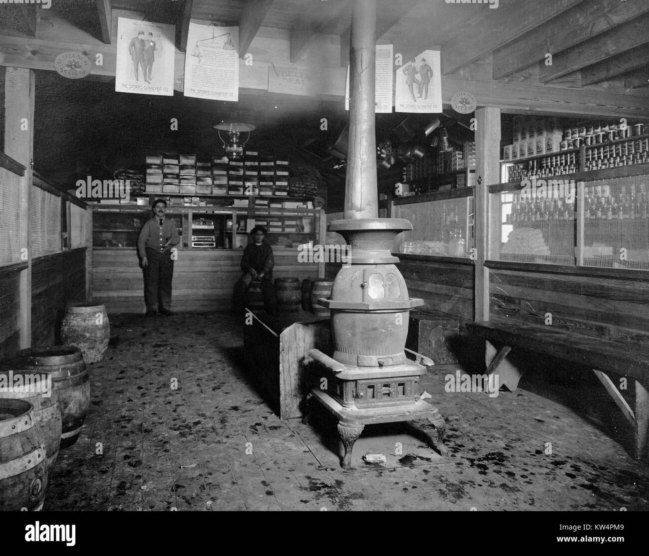 Due uomini stand all'interno di un negozio situato in un accampamento di acquedotto a lavoratori durante la costruzione di un acquedotto di Catskill, New York, Stati Uniti, gennaio 20, 1910. Dalla Biblioteca Pubblica di New York. Foto Stock
