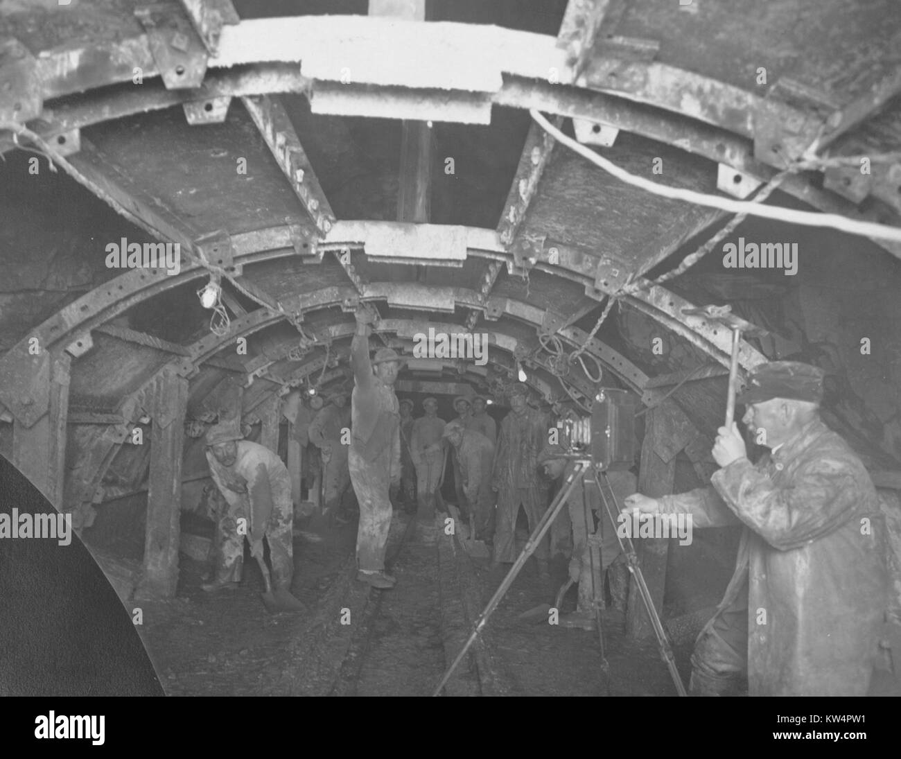 Fotografo scattare una fotografia dei lavoratori nella pressione rondout tunnel, che mostra il metodo di immissione di cemento in arco, New York, 1912. Dalla Biblioteca Pubblica di New York. Foto Stock