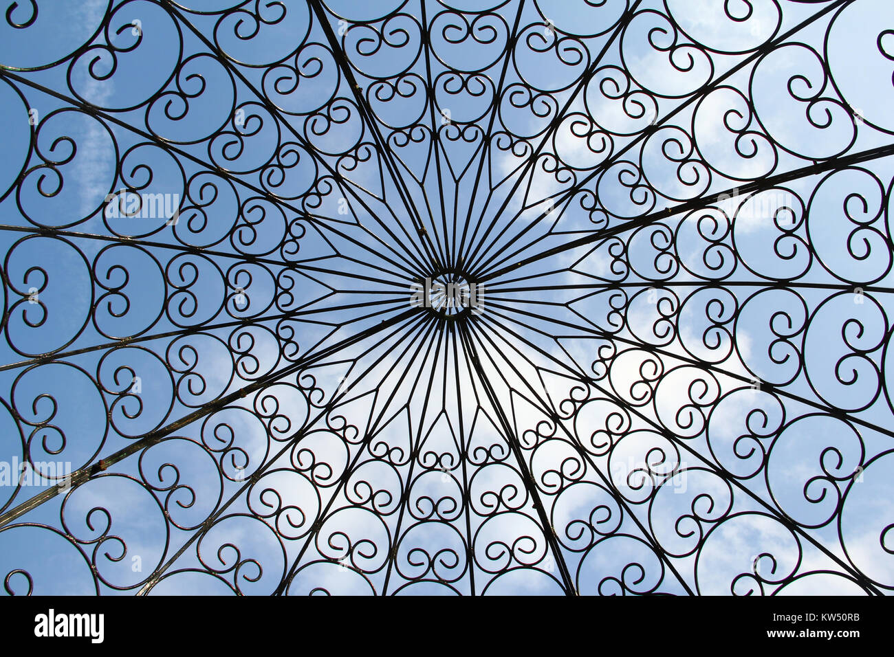 Vista verso l'alto di modelli astratti di un ferro battuto gazebo contro un cielo blu con luce cloud. Foto Stock