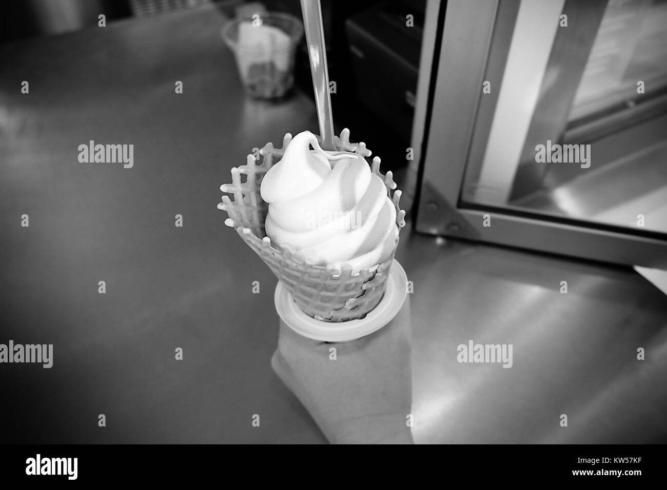 Una fotografia vintage in bianco e nero di un cono gelato che cattura un momento semplice ma iconico. L'immagine evoca nostalgia e rappresenta il classico piacere di molti in tutto il mondo. Foto Stock