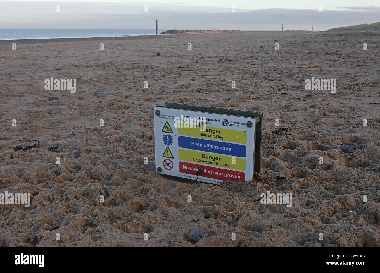 Segnali di avvertimento di pericoli connessi con le difese del mare, parzialmente sepolto sulla spiaggia Eccles-on-Sea, Norfolk, Regno Unito Dicembre Foto Stock