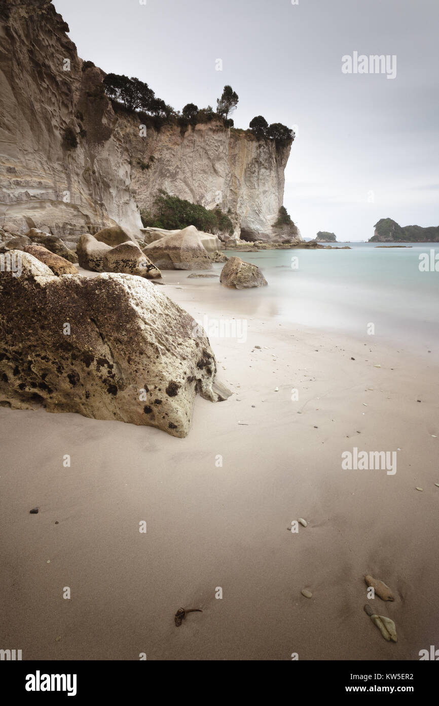 Tra scogliere sul mare, sabbia e massi su un suggestivo nebbioso giorno Sulla Coromandel, Isola del nord, Nuova Zelanda Foto Stock