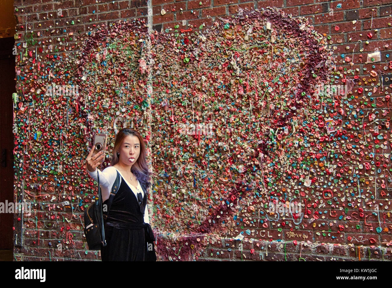 Donna asiatica tenendo selfie davanti al muro di gomma, Seattle, Washington, Stati Uniti d'America Foto Stock